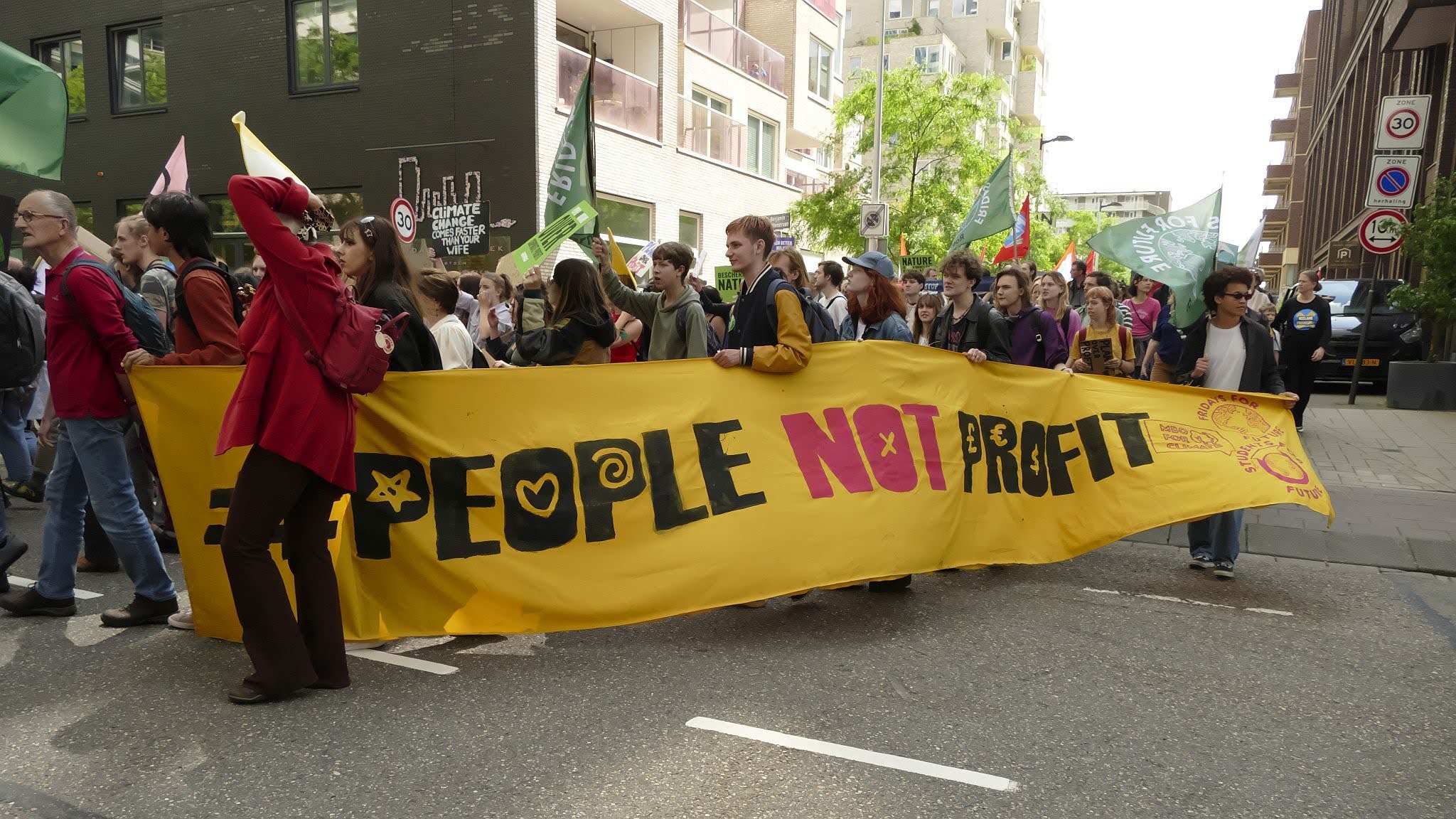 mensen marsen met “people not profit” spandoek