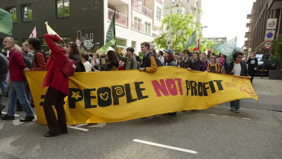 mensen marsen met “people not profit” spandoek
